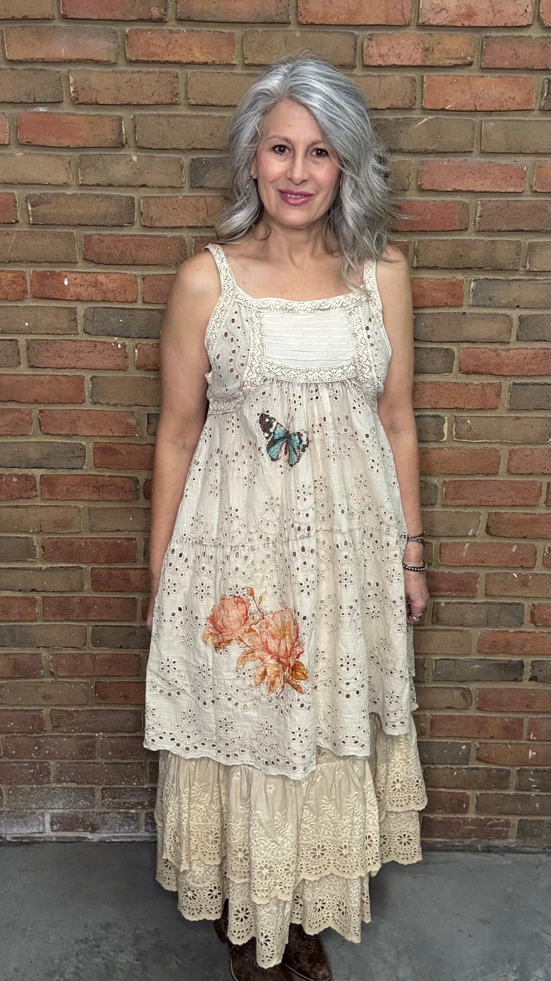 Woman wearing a Eyelet Lace Applique Dress with Serendipity Lace Maxi Skirt against a brick wall