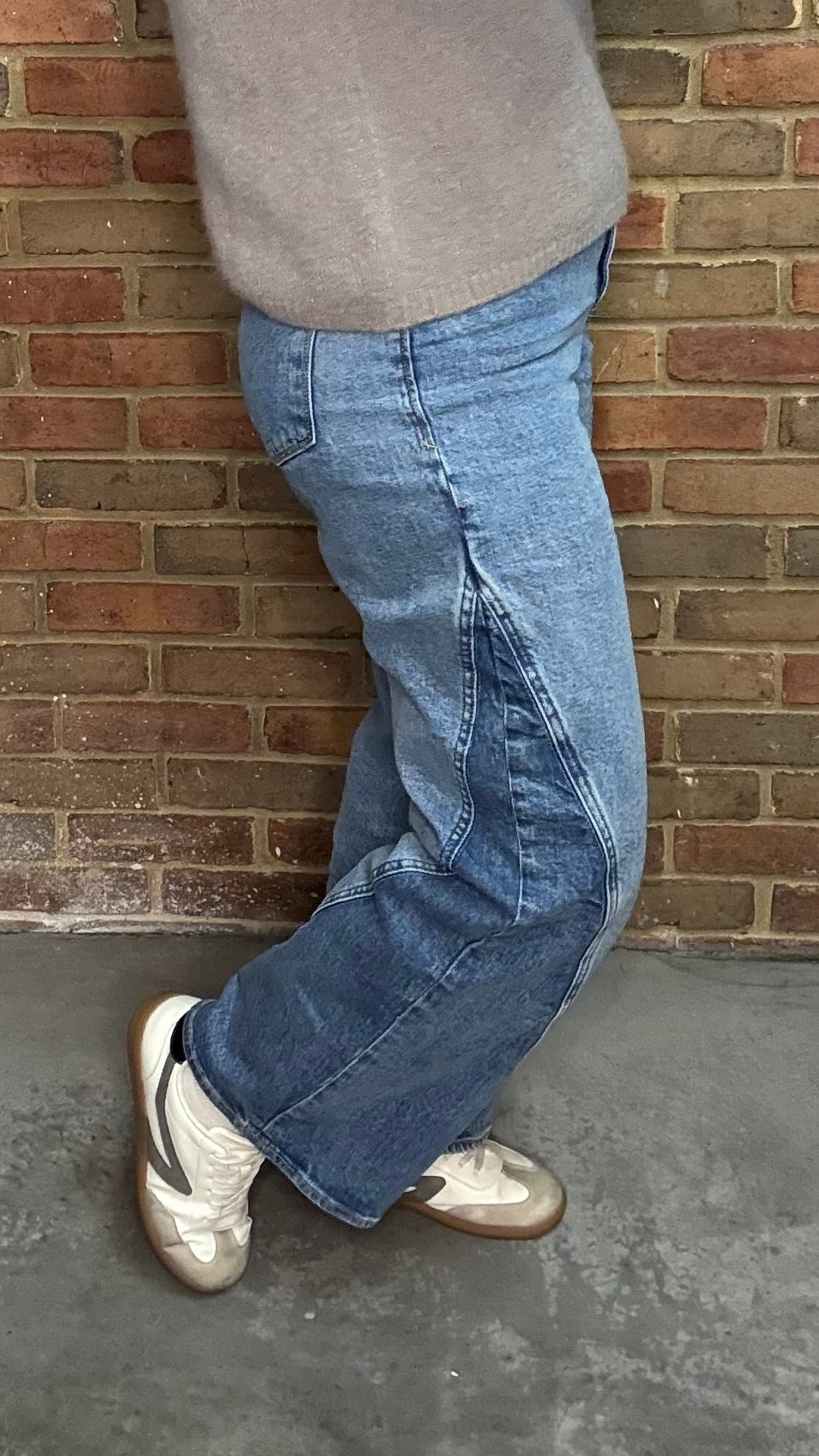 Woman in the HOLLY Super High Rise Two Tone Straight Jean casual outfit standing against a brick wall