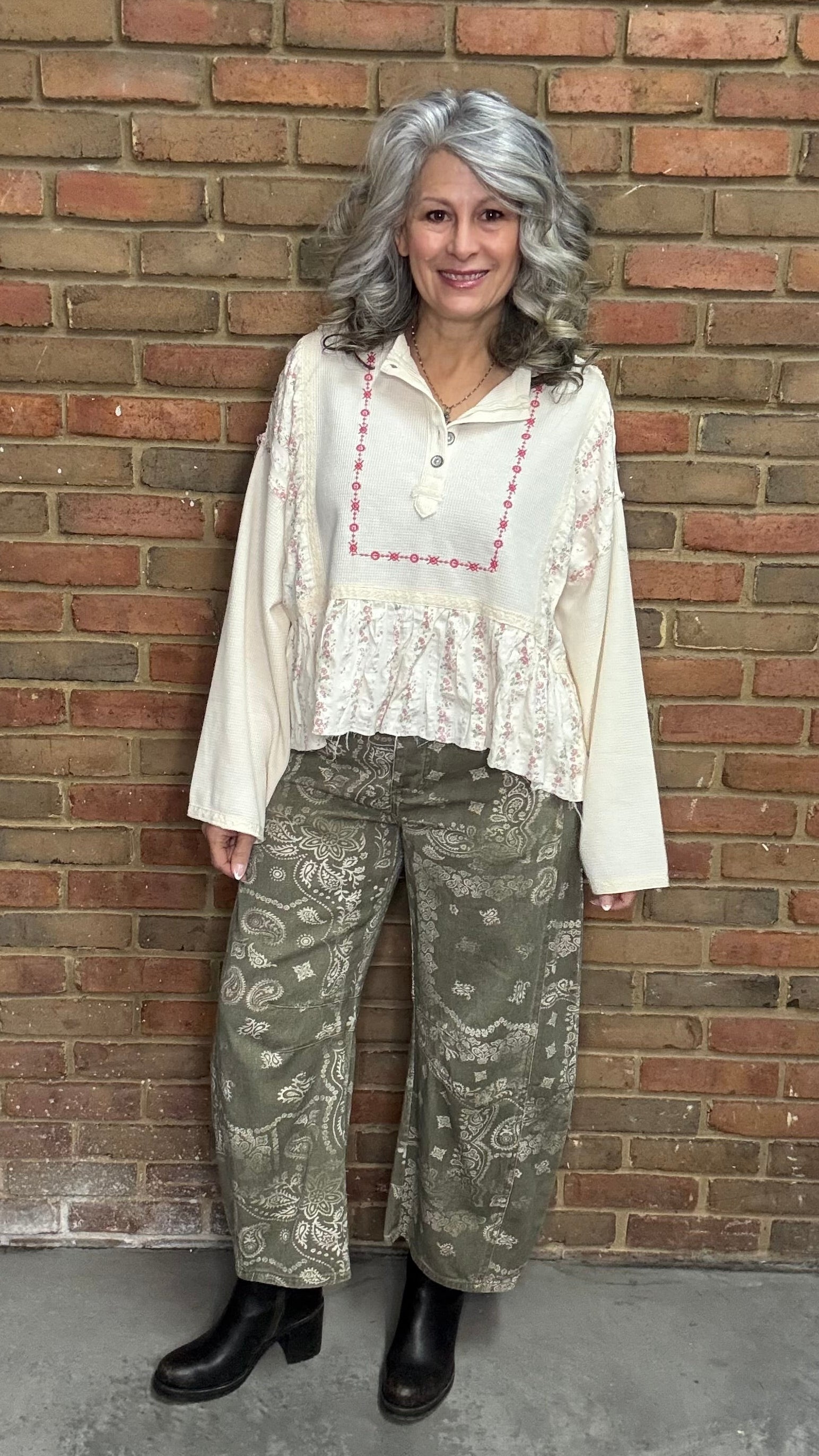Woman wearing the Natural Flare Sleeve Mix Media Top and Paisley Print Barrel Jean standing against a brick wall.