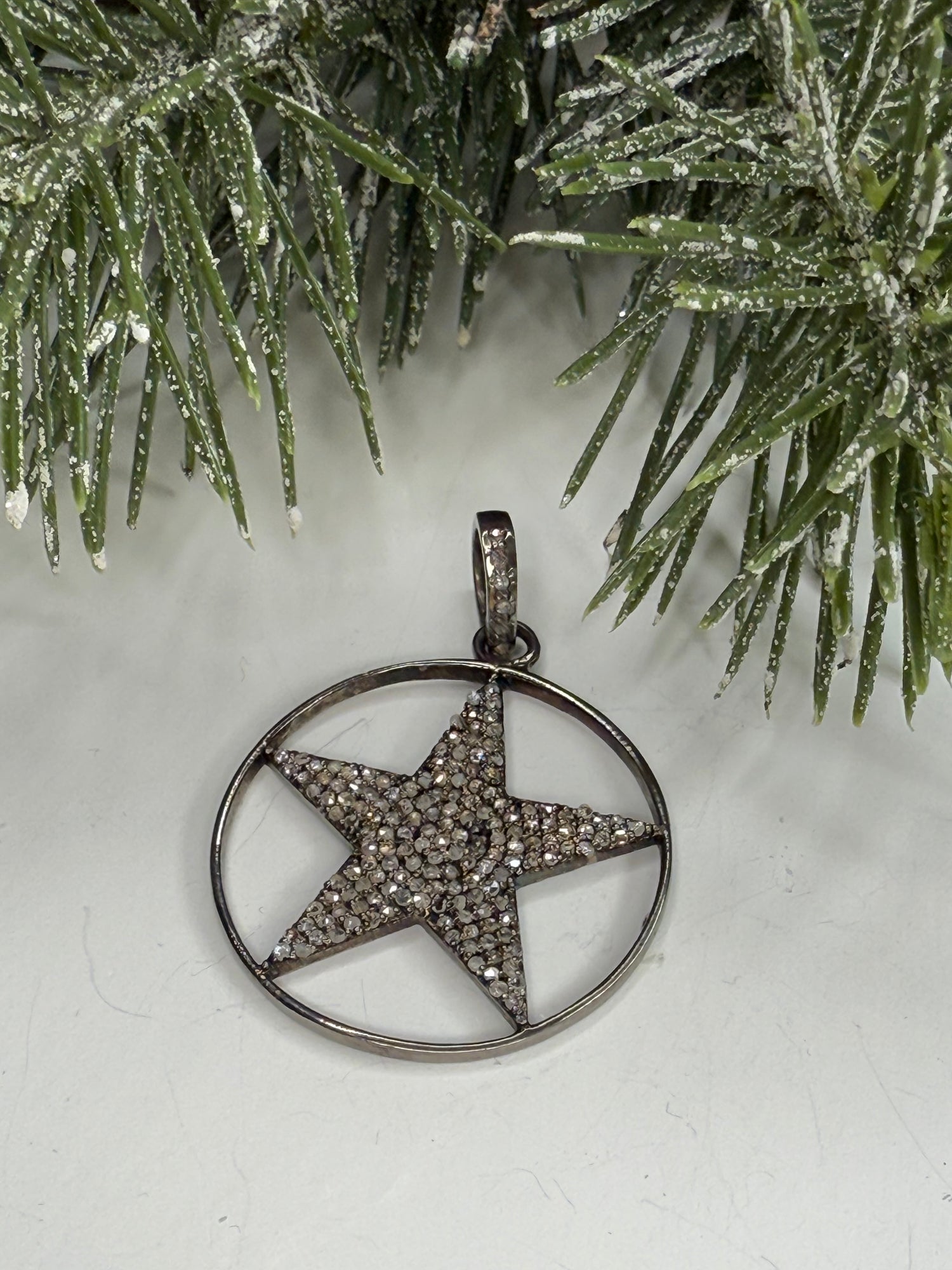 Lone Star pendant with pave diamonds on a white surface with greenery