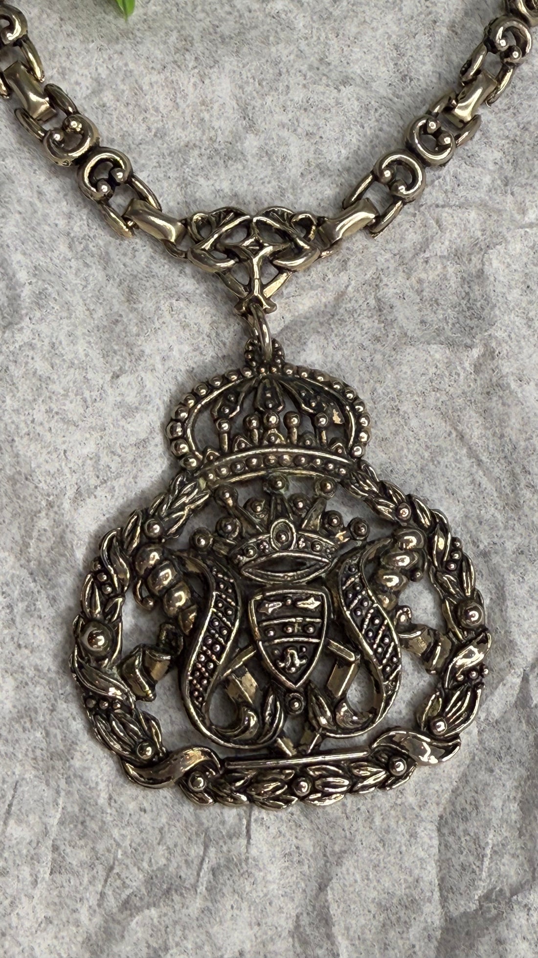 Decorative silver necklace with intricate design on a textured surface