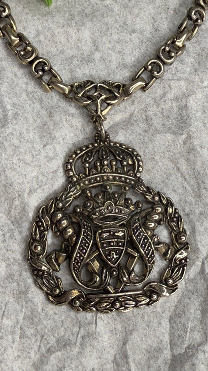 Decorative silver necklace with intricate design on a textured surface