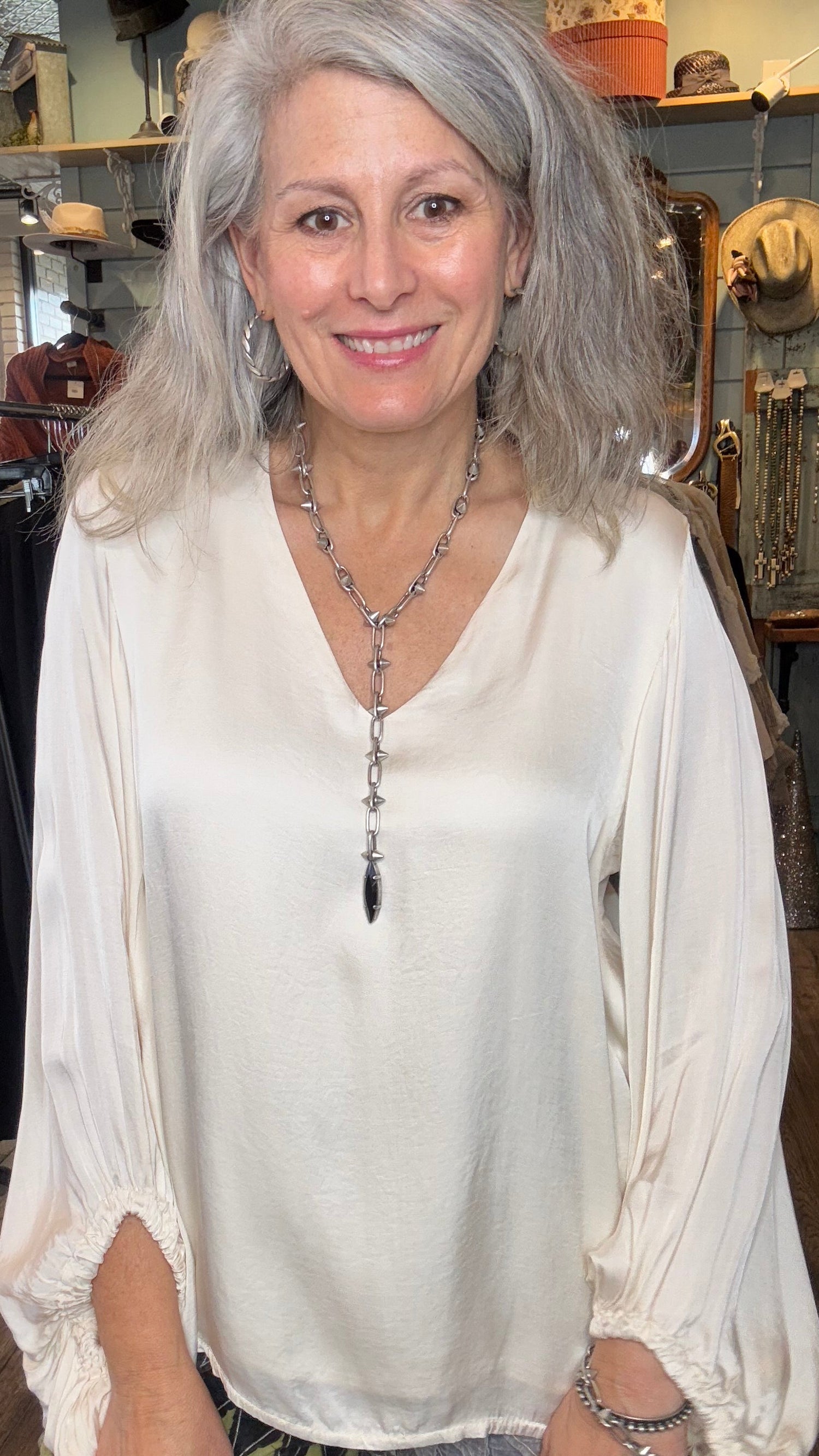Woman wearing a white blouse with a necklace in an indoor setting