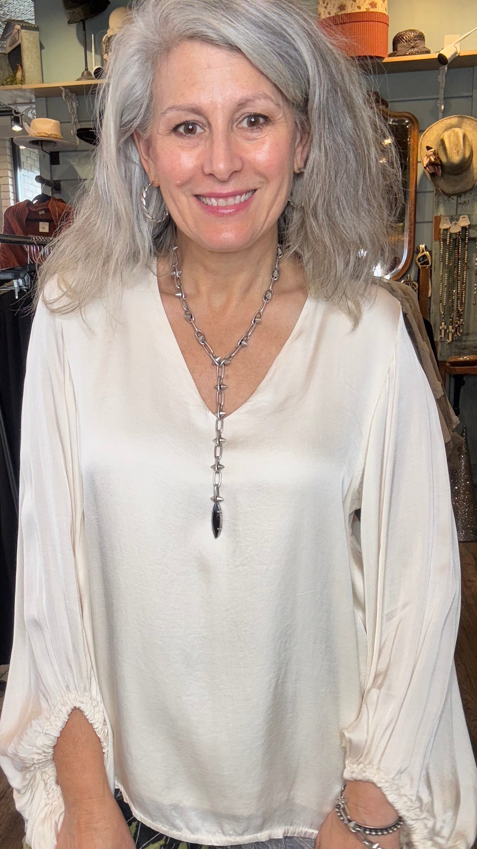 Woman wearing a white blouse with a necklace in an indoor setting