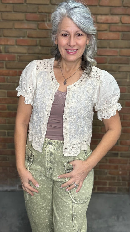 Woman wearing the Crochet Embroidery Button-Up Top and Floral Printed Barrel Pants with a brick wall background