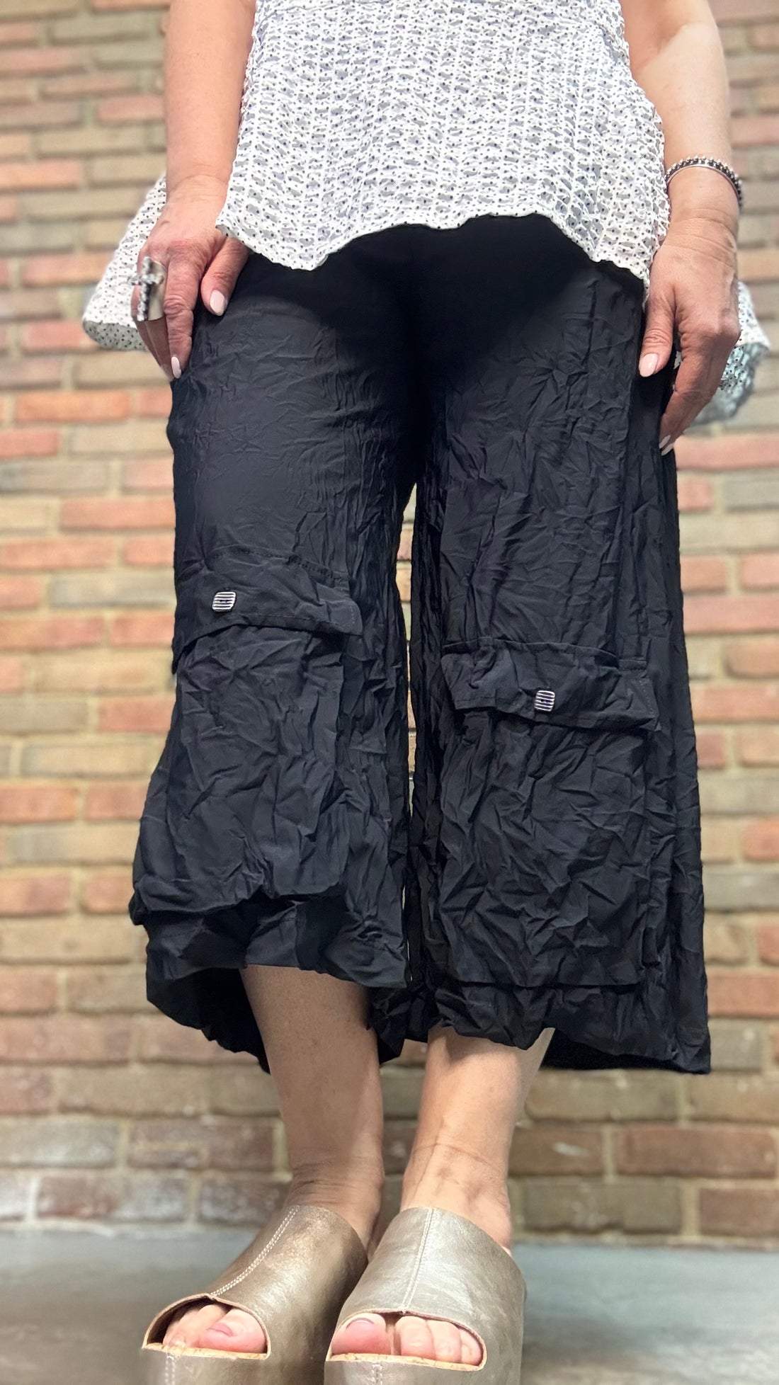 Person wearing Lissie Pant - Blacks and a white top against a brick wall.
