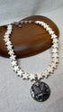 Necklace with star-shaped beads and a central pendant on a wooden stand.