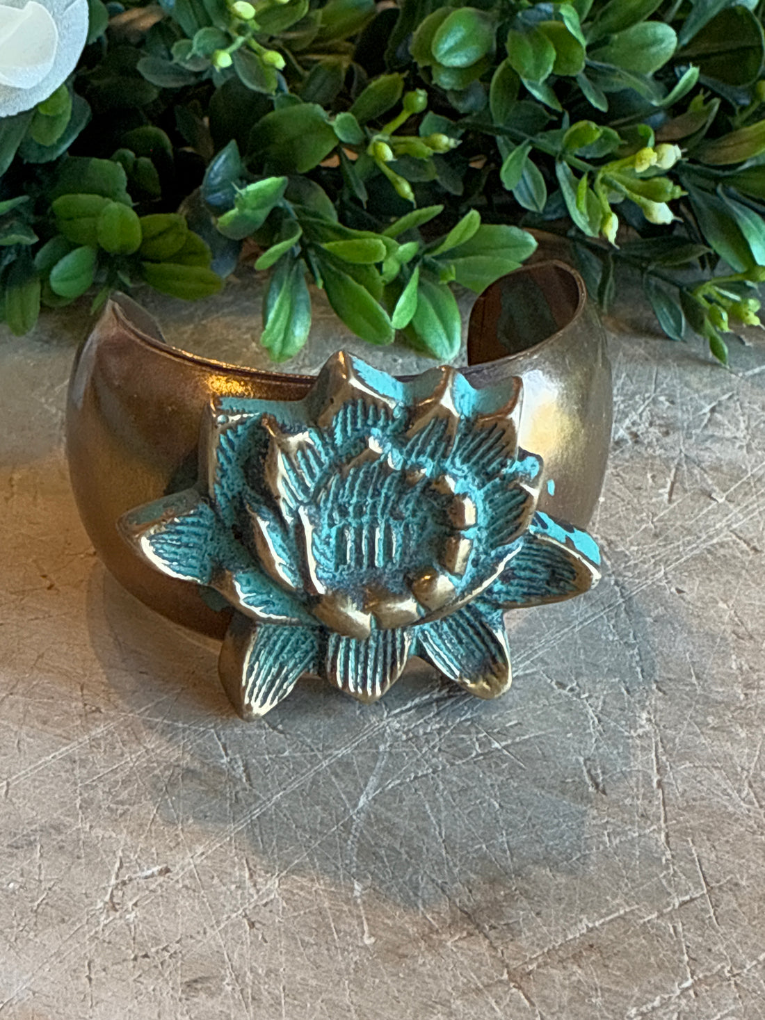 Brass Lotus Cuff on a textured surface with greenery