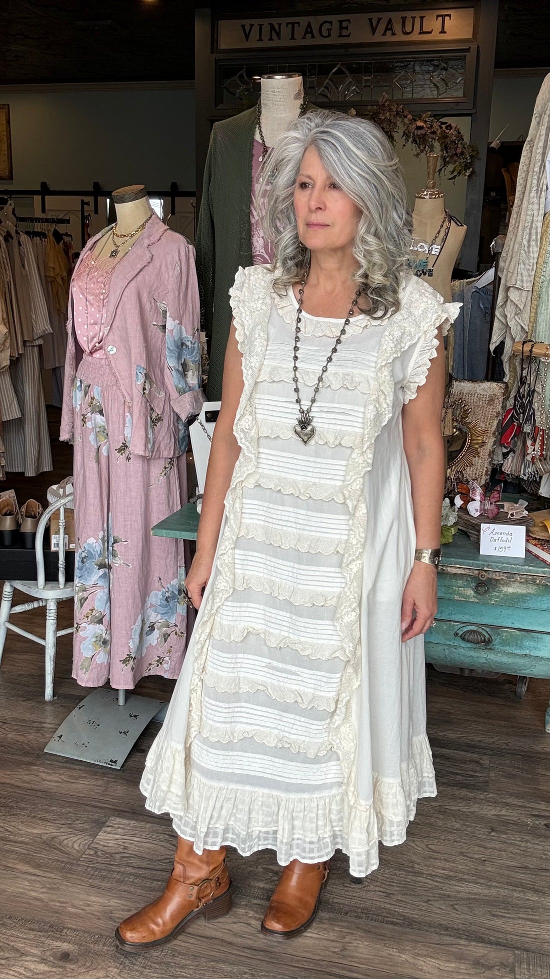 Woman in the ANCOLIE - ECRU DRESS, a off-white dress standing in Vintage Vault with clothing displays in the background.