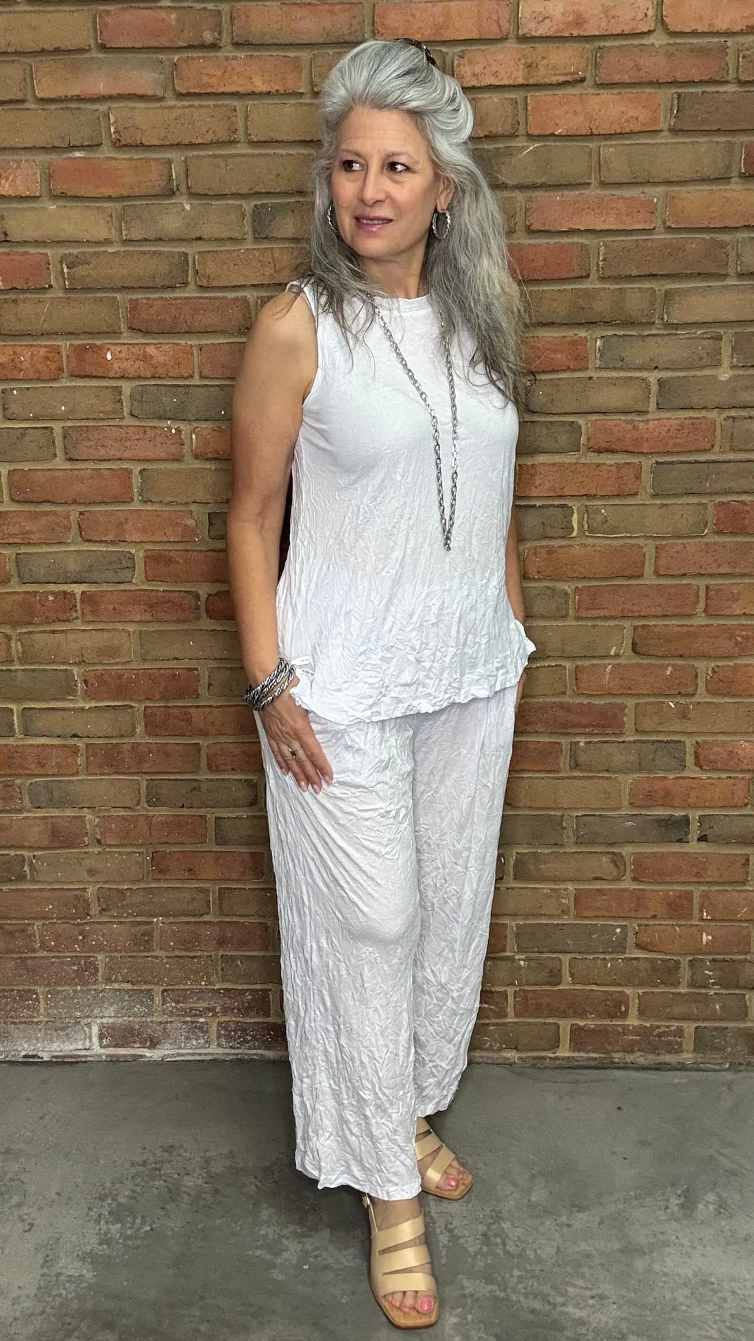 Woman wearing White Capri Straight Leg Pant standing against a brick wall.