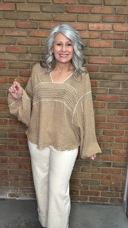 Woman wearing Mocha and Ivory Print Long Sleeve Top and blue jeans standing against a brick wall.
