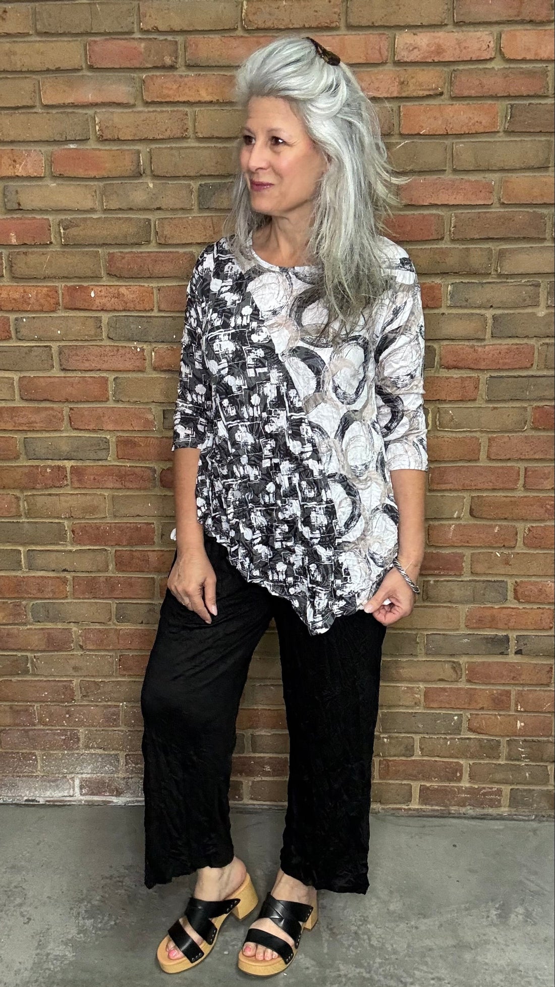 Woman wearing Circles Asymmetric Pocket Top standing in front of a brick wall.