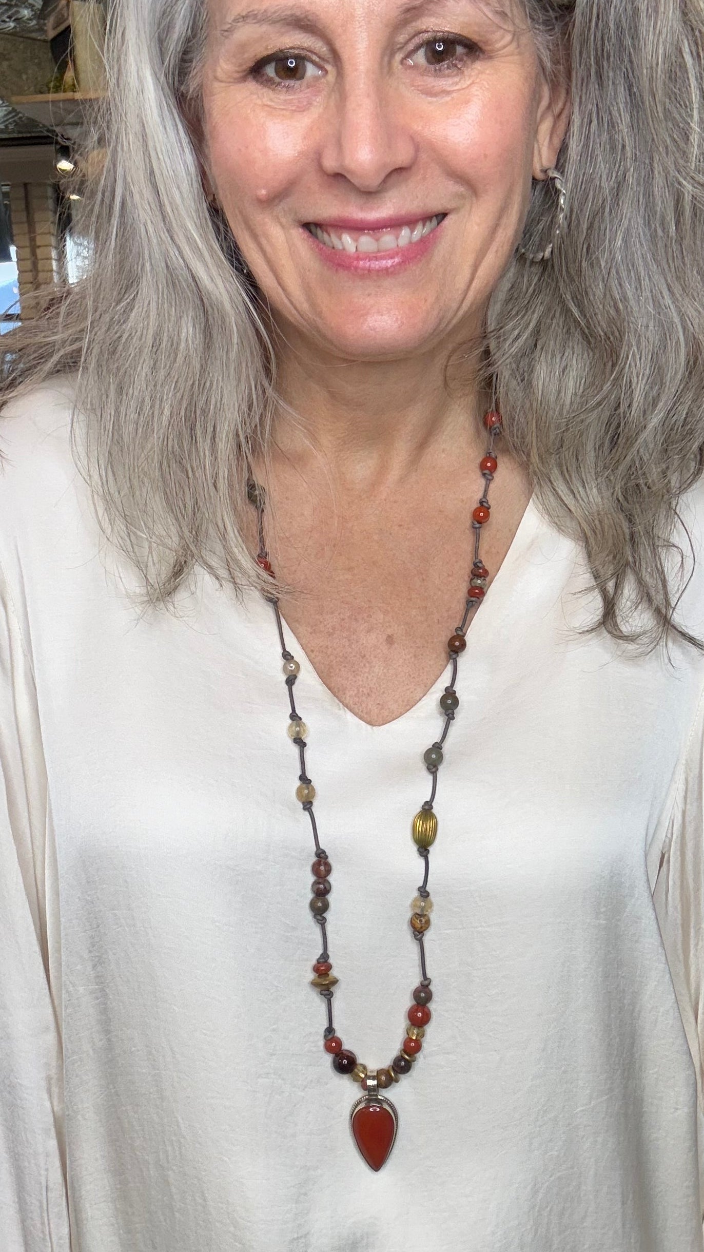 Woman wearing a white blouse and a necklace with a blurred indoor background