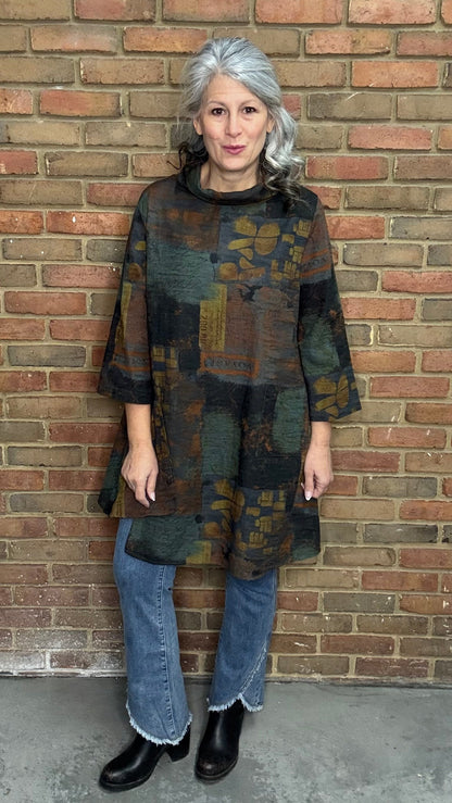 Woman wearing Blythe Tawn Tunic and  the Front Tulip Hem Bootcut Pant jeans standing against a brick wall.