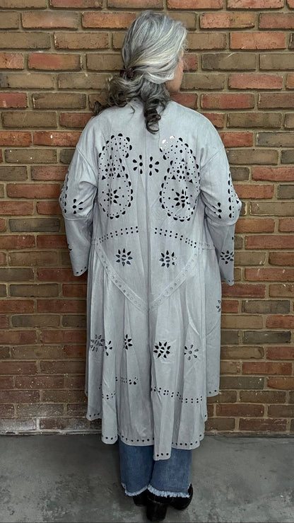 Woman wearing the Grey Suede Laser Cut Jacket standing against a brick wall.