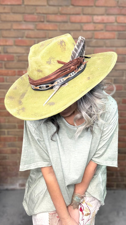 Woman wearing Spirit Feather Hat against a brick wall.