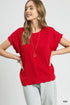 Woman wearing a red top and light jeans on a plain background
