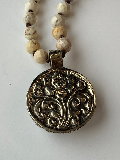 back of rose pendant on a beaded necklace with a white background