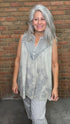 Woman wearing the Sage Floral Embroidery Tank Top, a light-colored sleeveless top with a pattern against a brick wall.