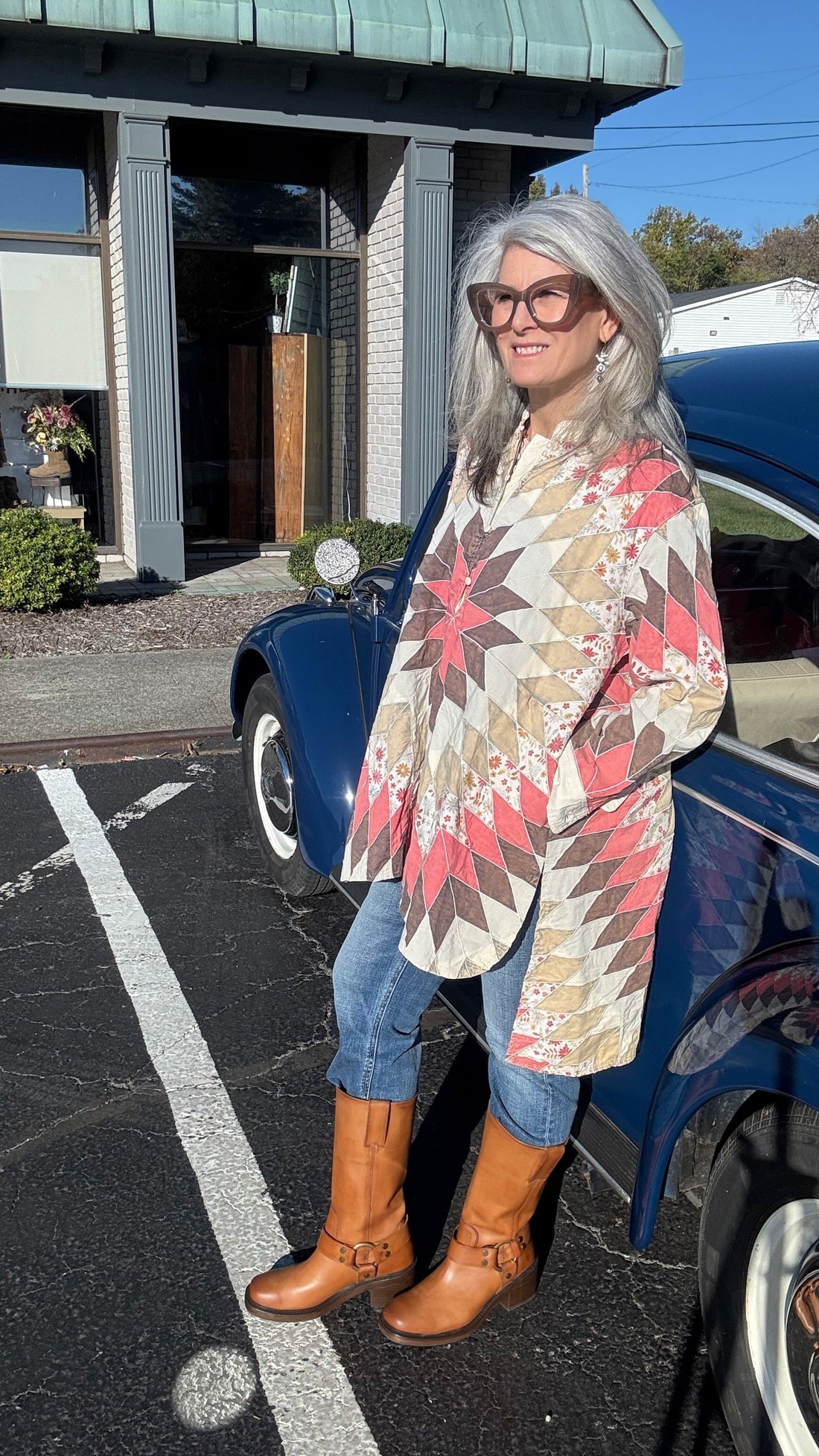 Woman standing next to a blue car on a street with buildings in the background
