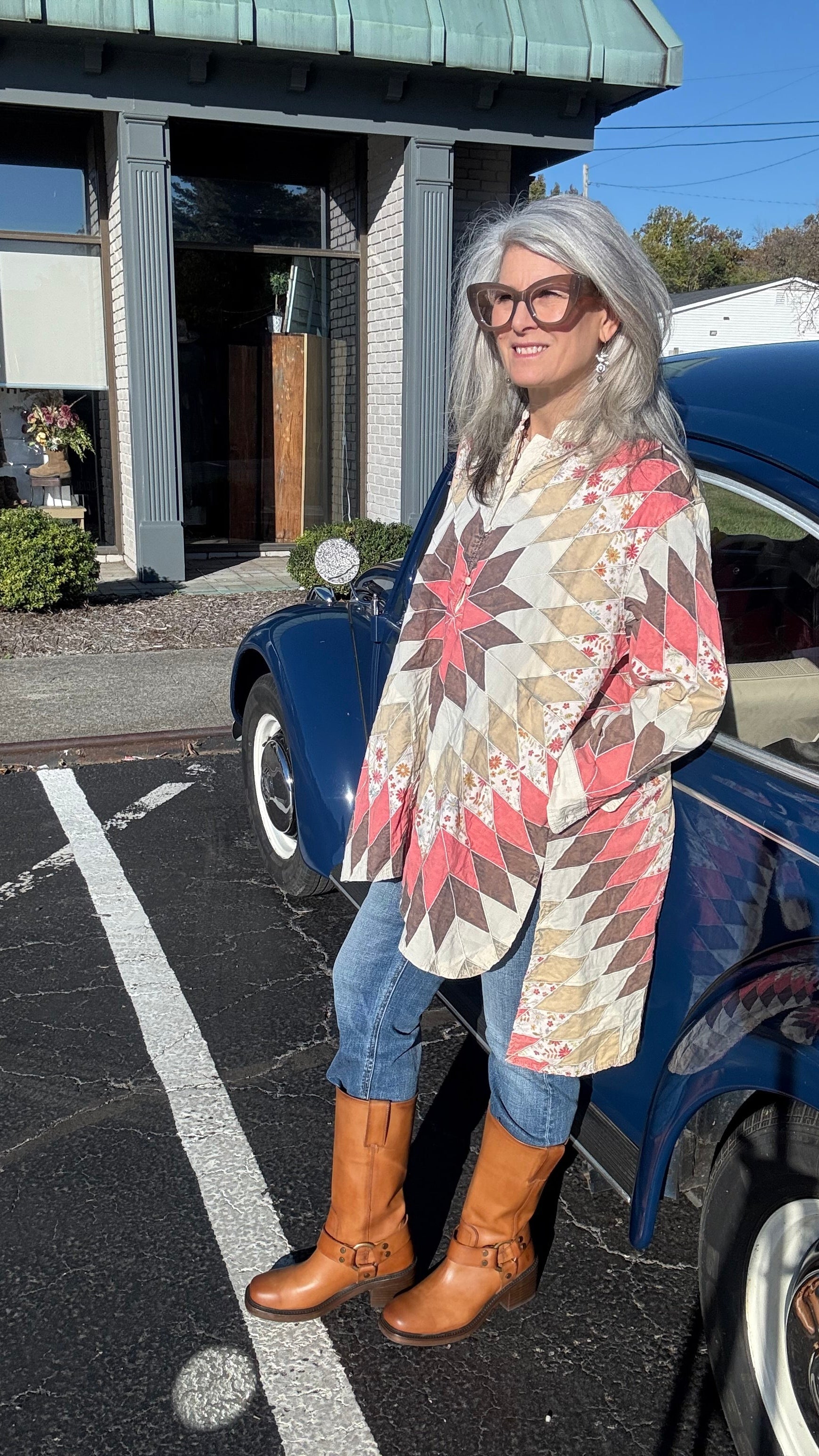 Woman standing next to a blue car on a street with buildings in the background