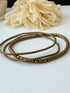 Bronze beaded bracelets and beige flower on a white background