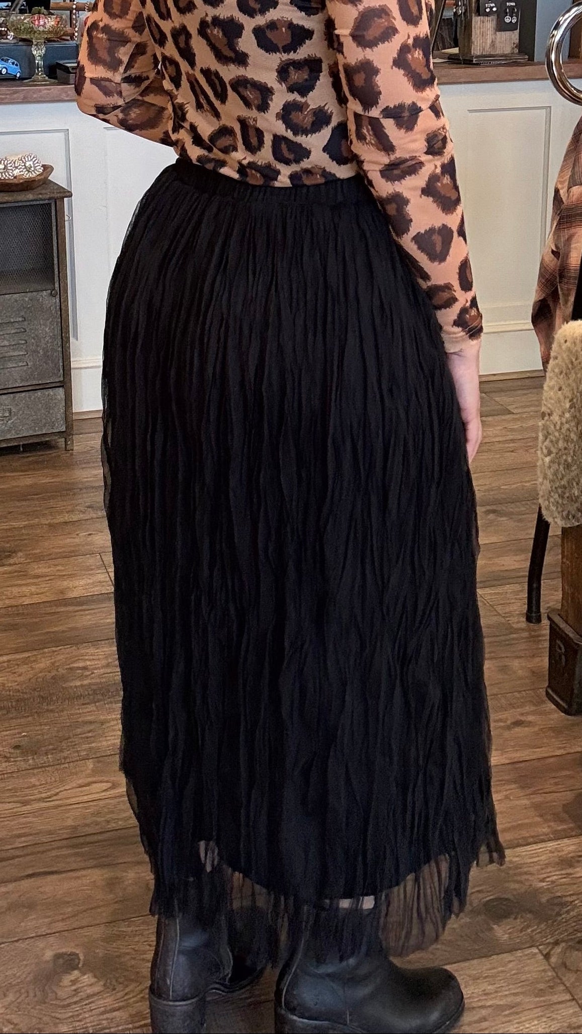 Person wearing a leopard print top and black skirt in a store setting