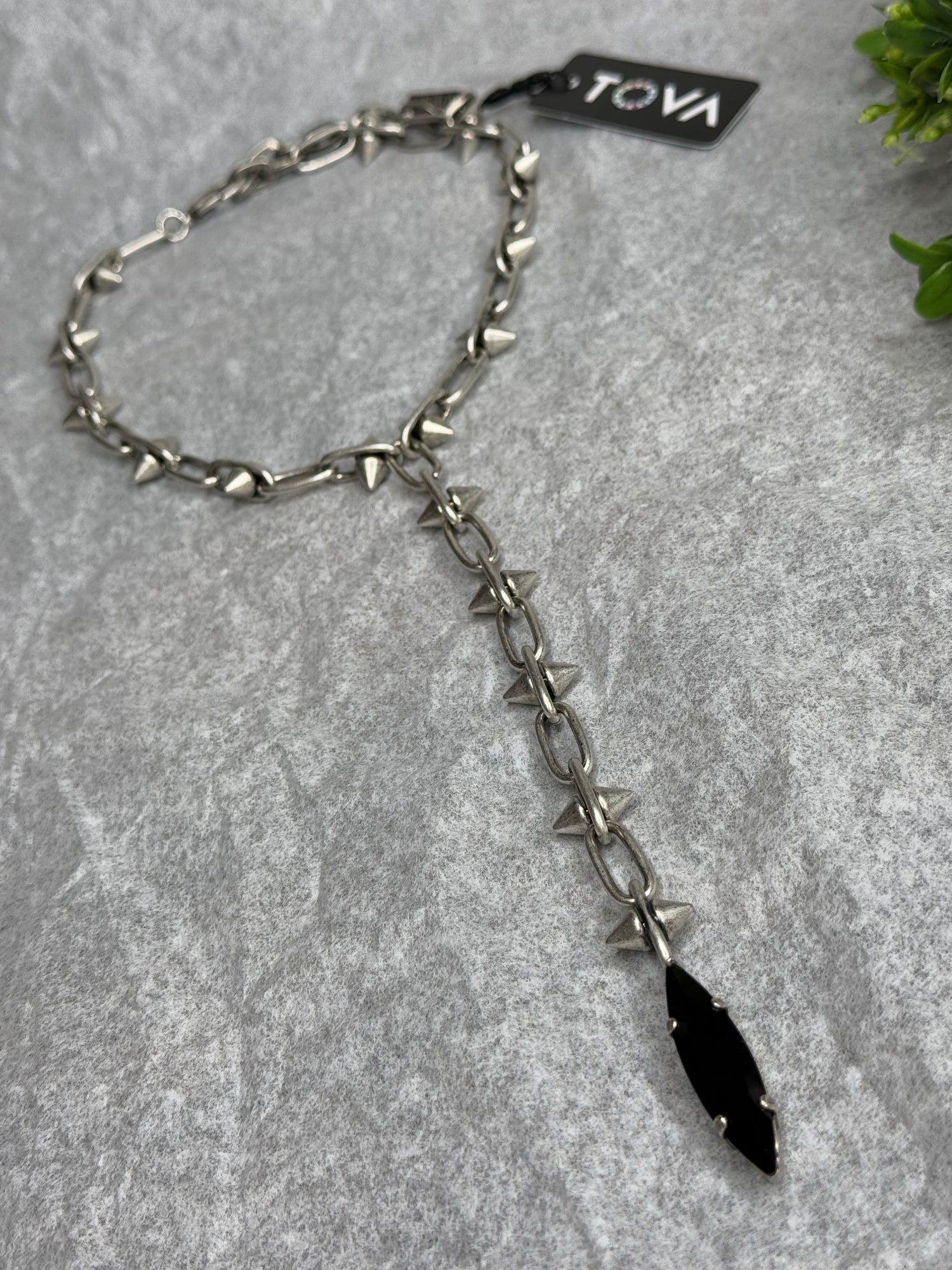 Silver chain with black pendant on a gray surface