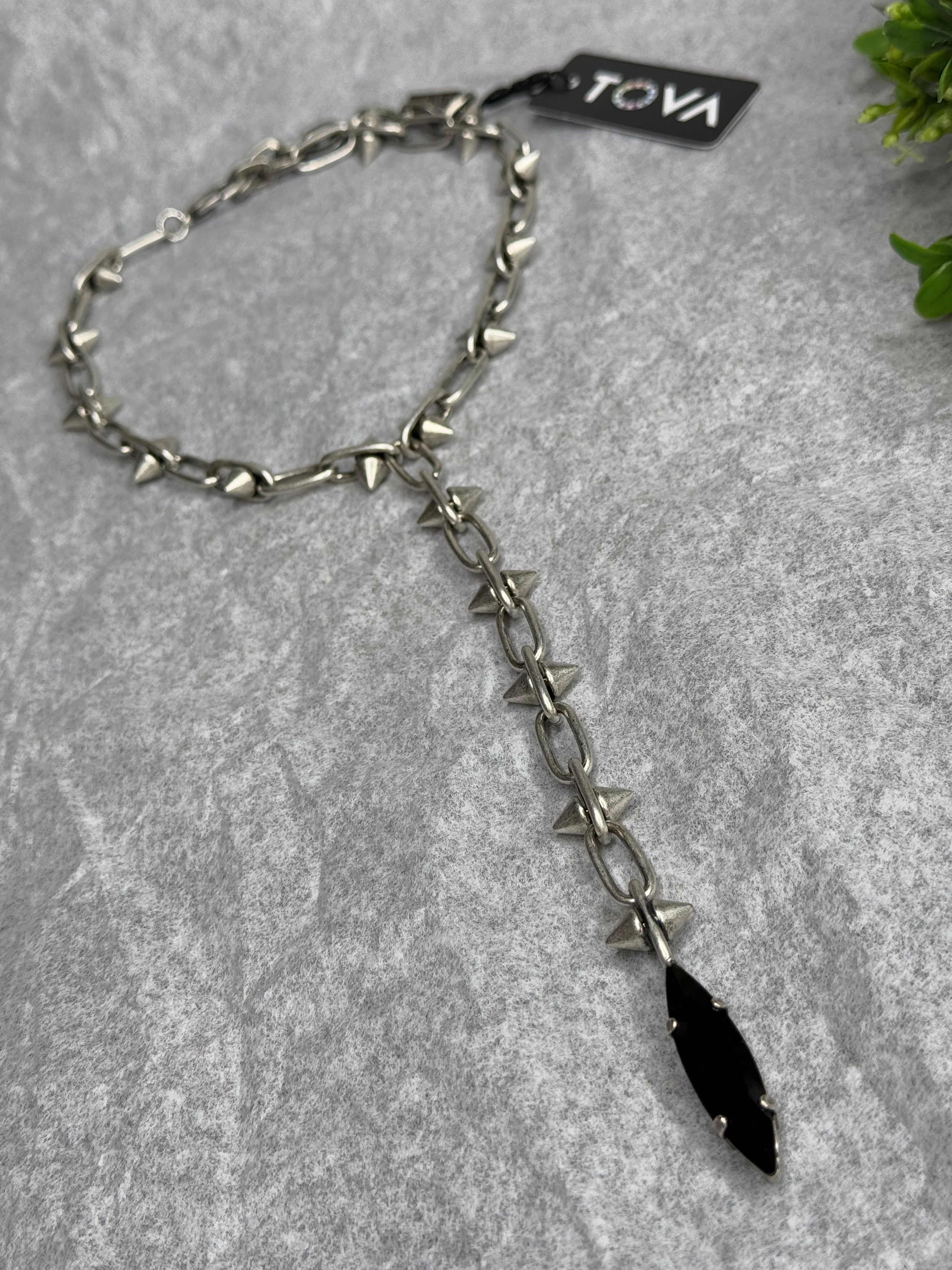Silver chain with black pendant on a gray surface