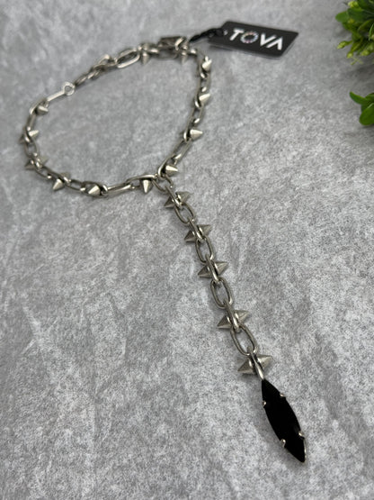 Silver chain with black pendant on a gray surface