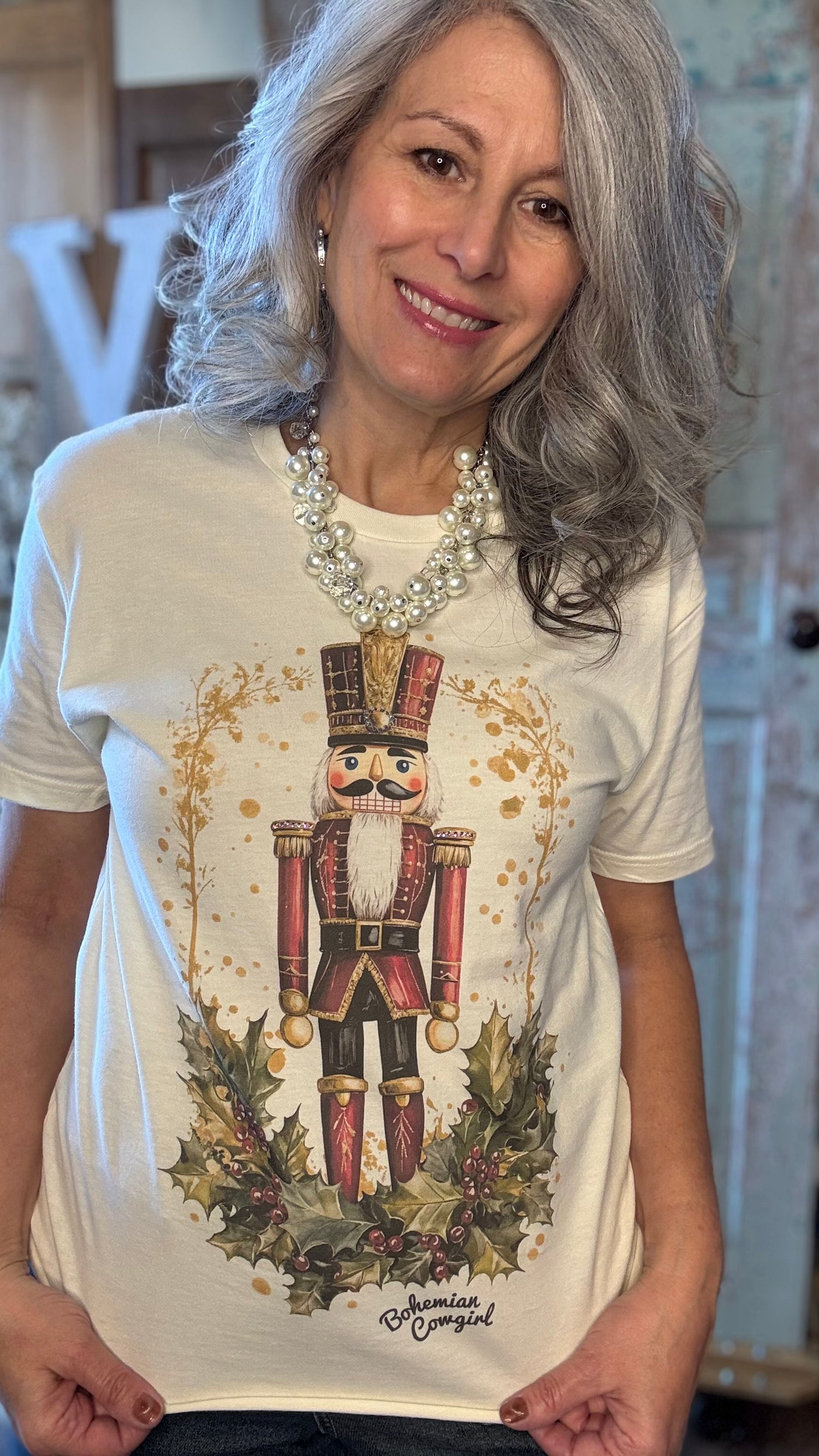 Woman wearing a white t-shirt with a nutcracker design in an indoor setting