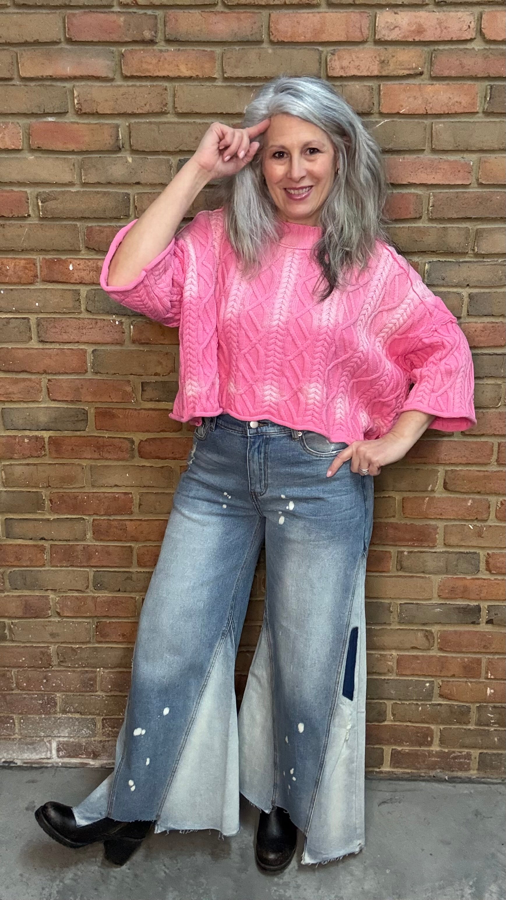 Woman wearing Bleached Wide Leg Jeans and Dusty Pink Ombre Sweater standing against a brick wall.