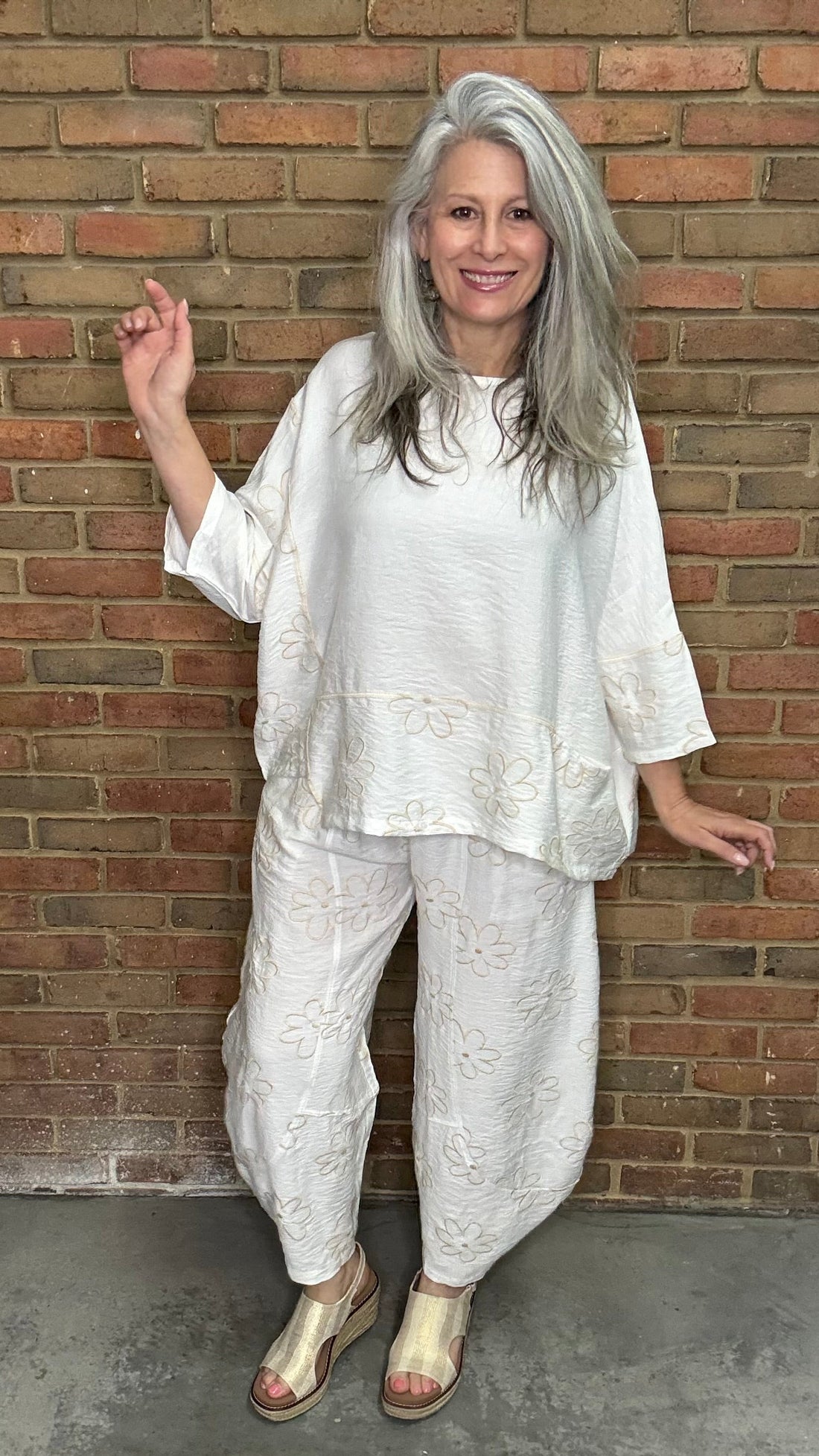 Woman in the Daisy Pant and Top Set standing against a brick wall