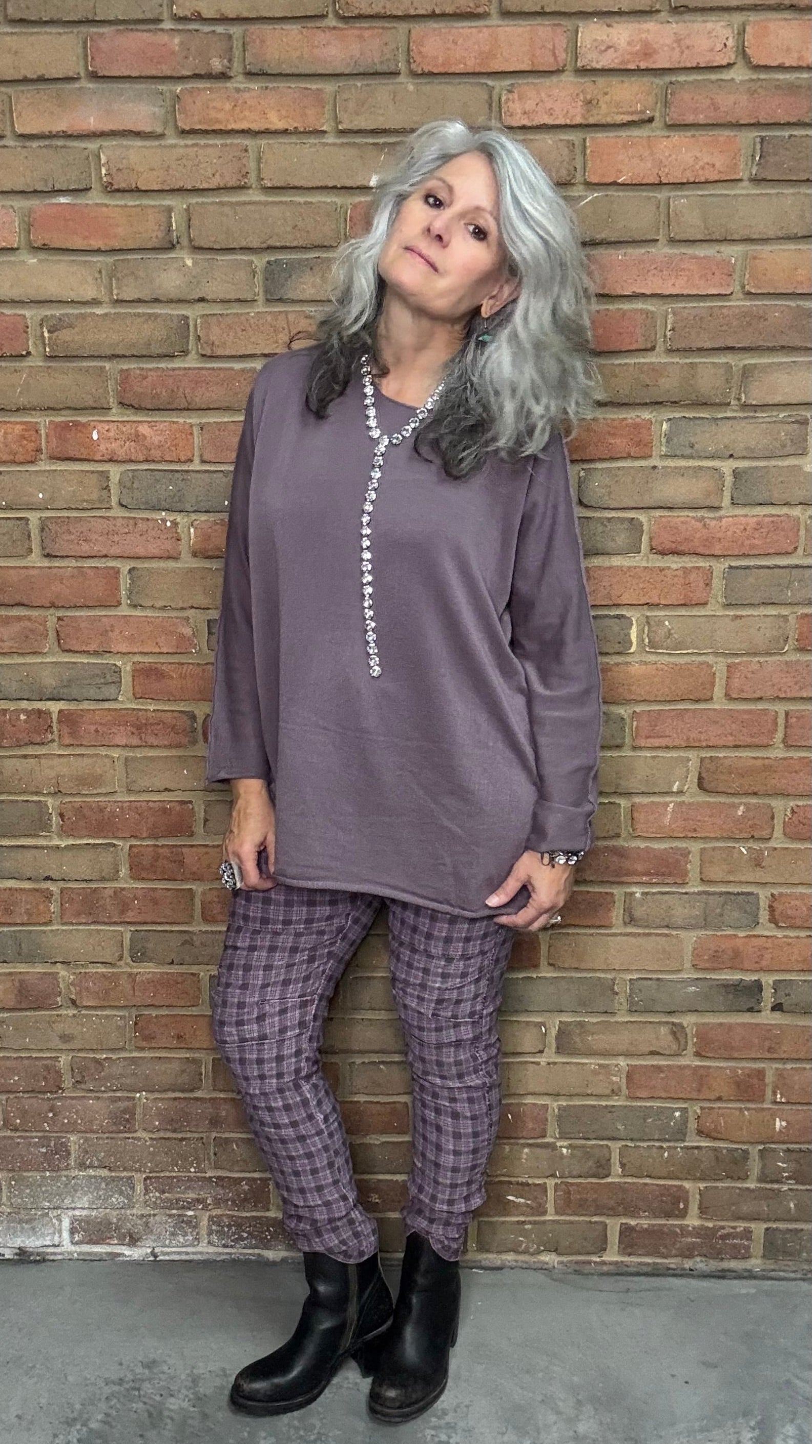 Person wearing a purple outfit standing against a brick wall
