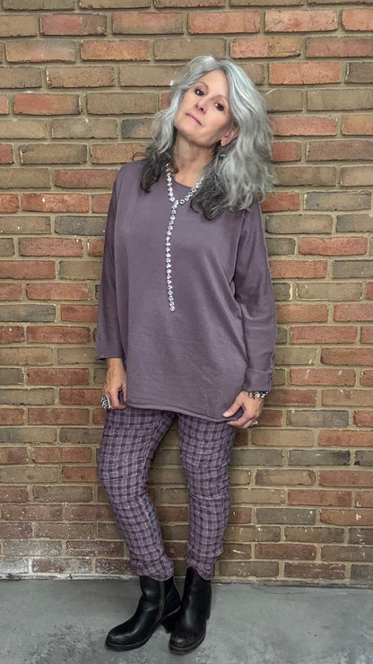 Person wearing a purple outfit standing against a brick wall