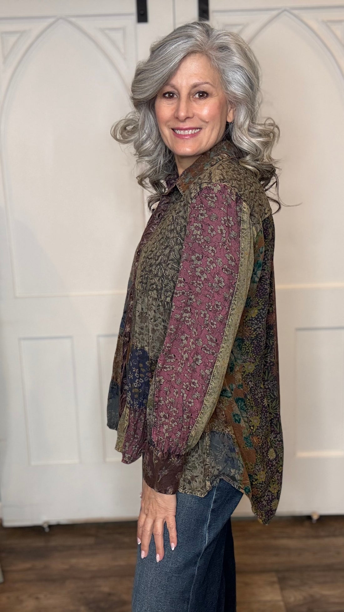Woman wearing the Amber Quilted Bodice and Tiers Top with jeans against a white wall.