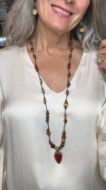 Woman wearing a beaded necklace with a close-up of the necklace on a white background