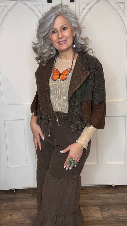 Woman wearing Boho Embroidered Lapel Crop Jacket, beige lace top with Monarch Butterfly Necklace and Amber Boho Chic pants against a white paneled wall.