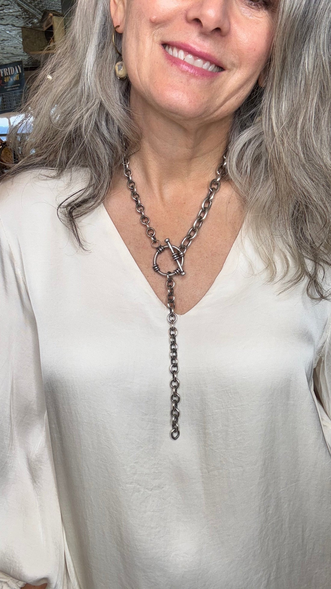 Woman wearing a white top and silver necklace with a blurred background