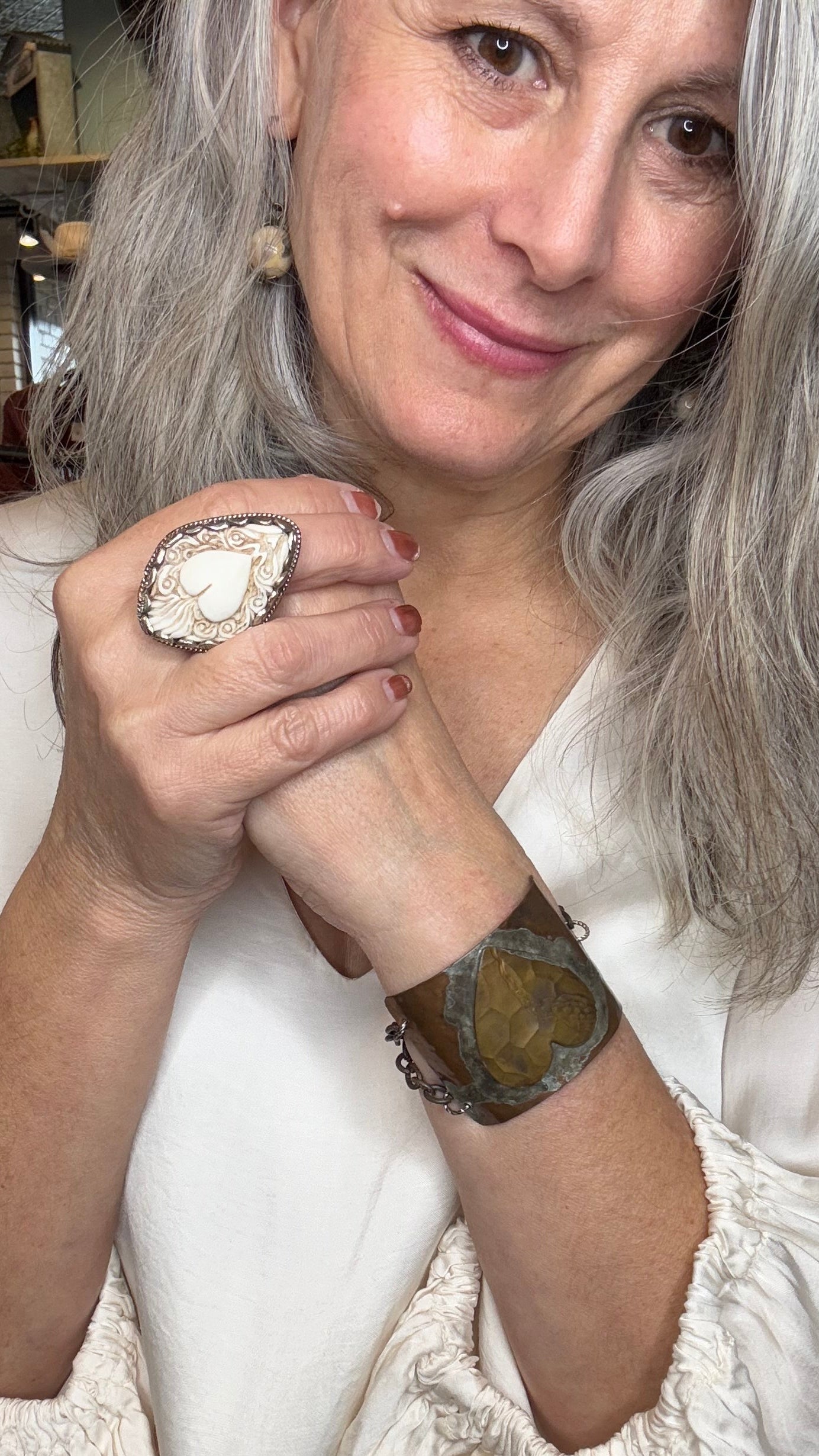Woman wearing a large ring with a textured surface, indoors.