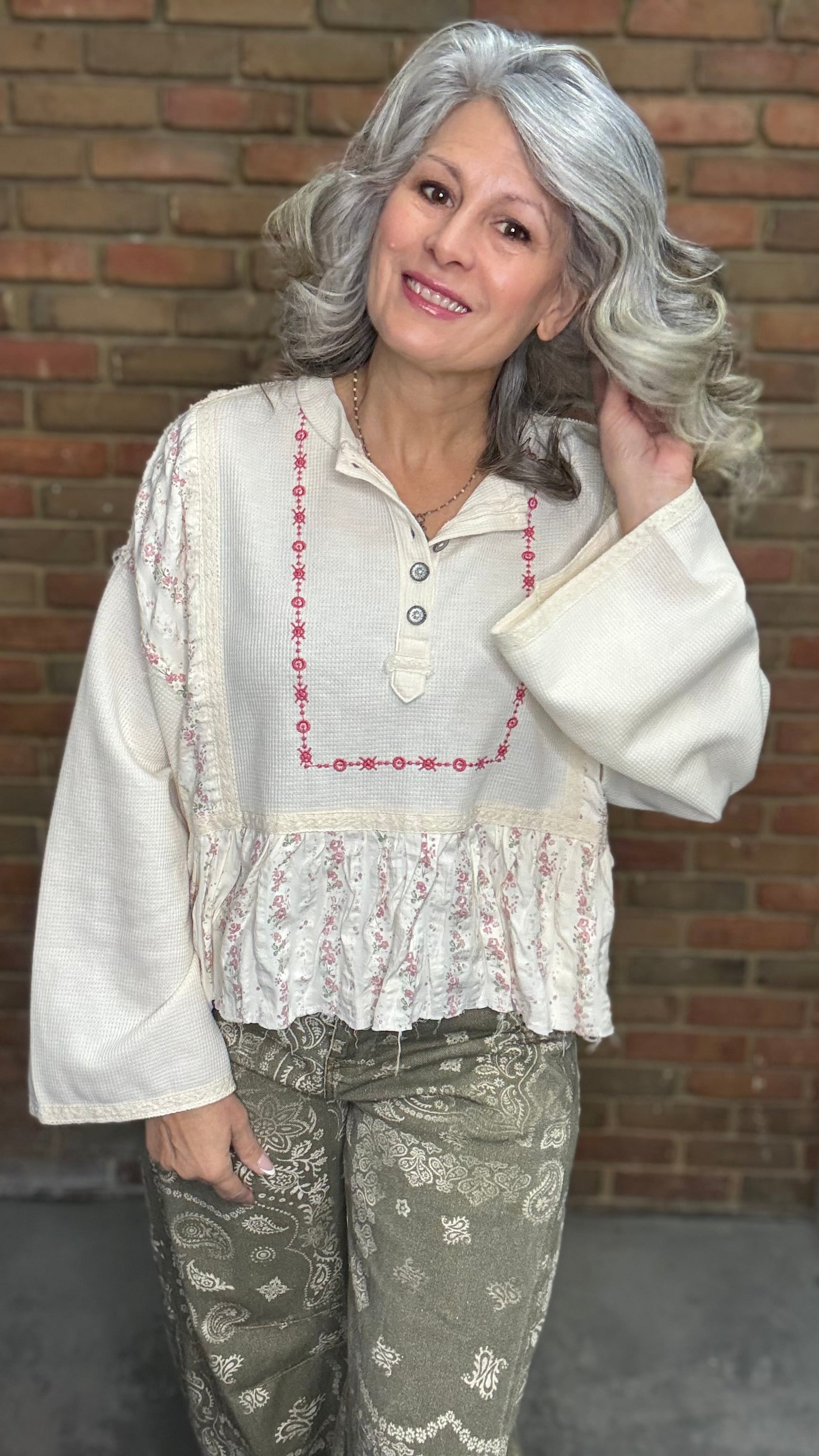 Woman wearing the Natural Flare Sleeve Mix Media Top and Paisley Print Barrel Jean standing against a brick wall.