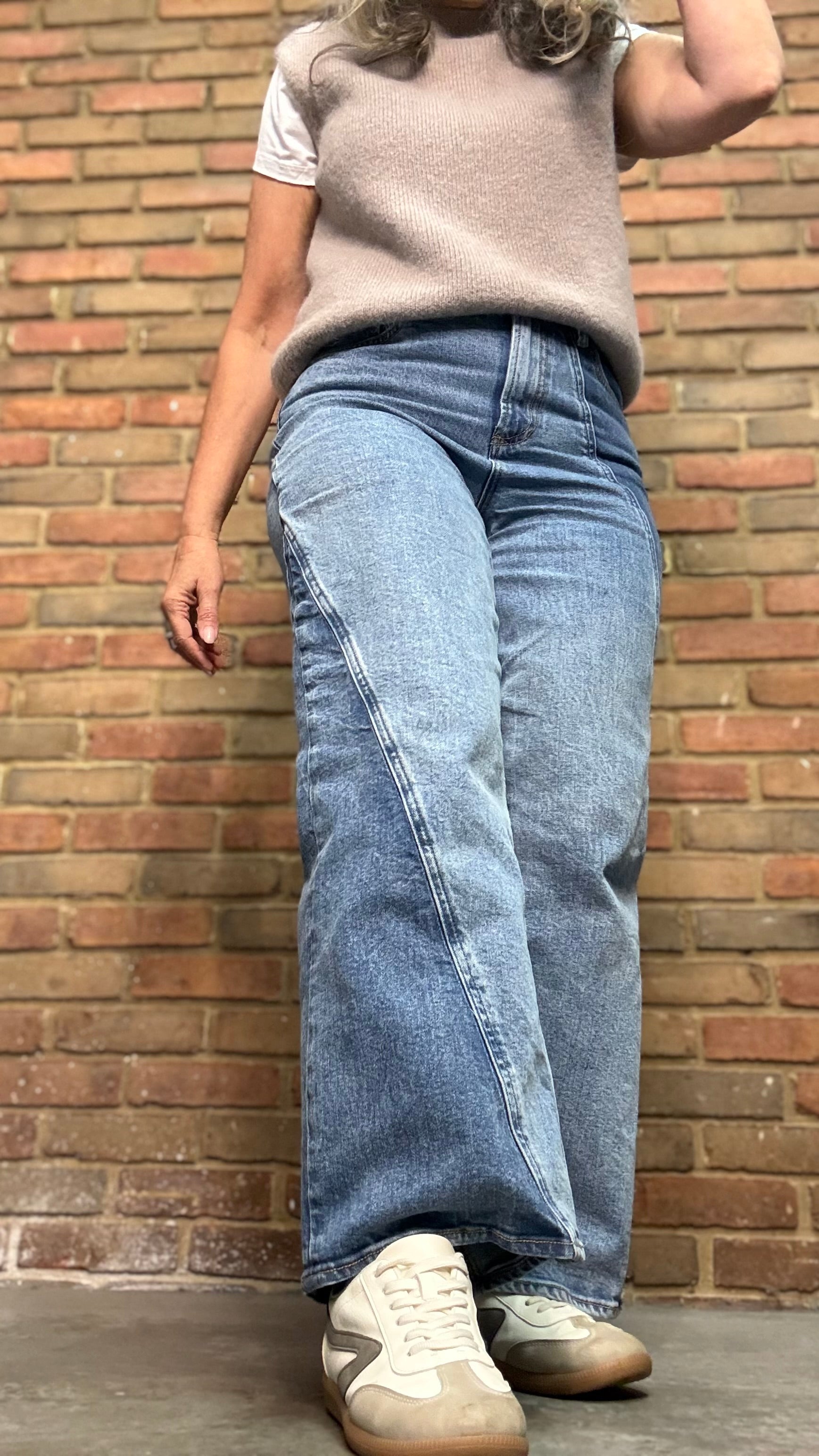 Woman in the HOLLY Super High Rise Two Tone Straight Jean casual outfit standing against a brick wall