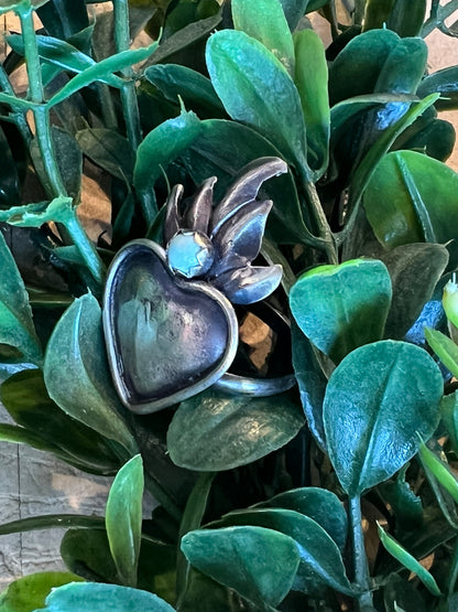 Flame Heart -T Ring on a green leafy background