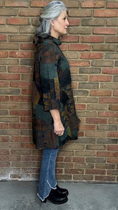 Woman wearing Blythe Tawn Tunic and  the Front Tulip Hem Bootcut Pant jeans standing against a brick wall.