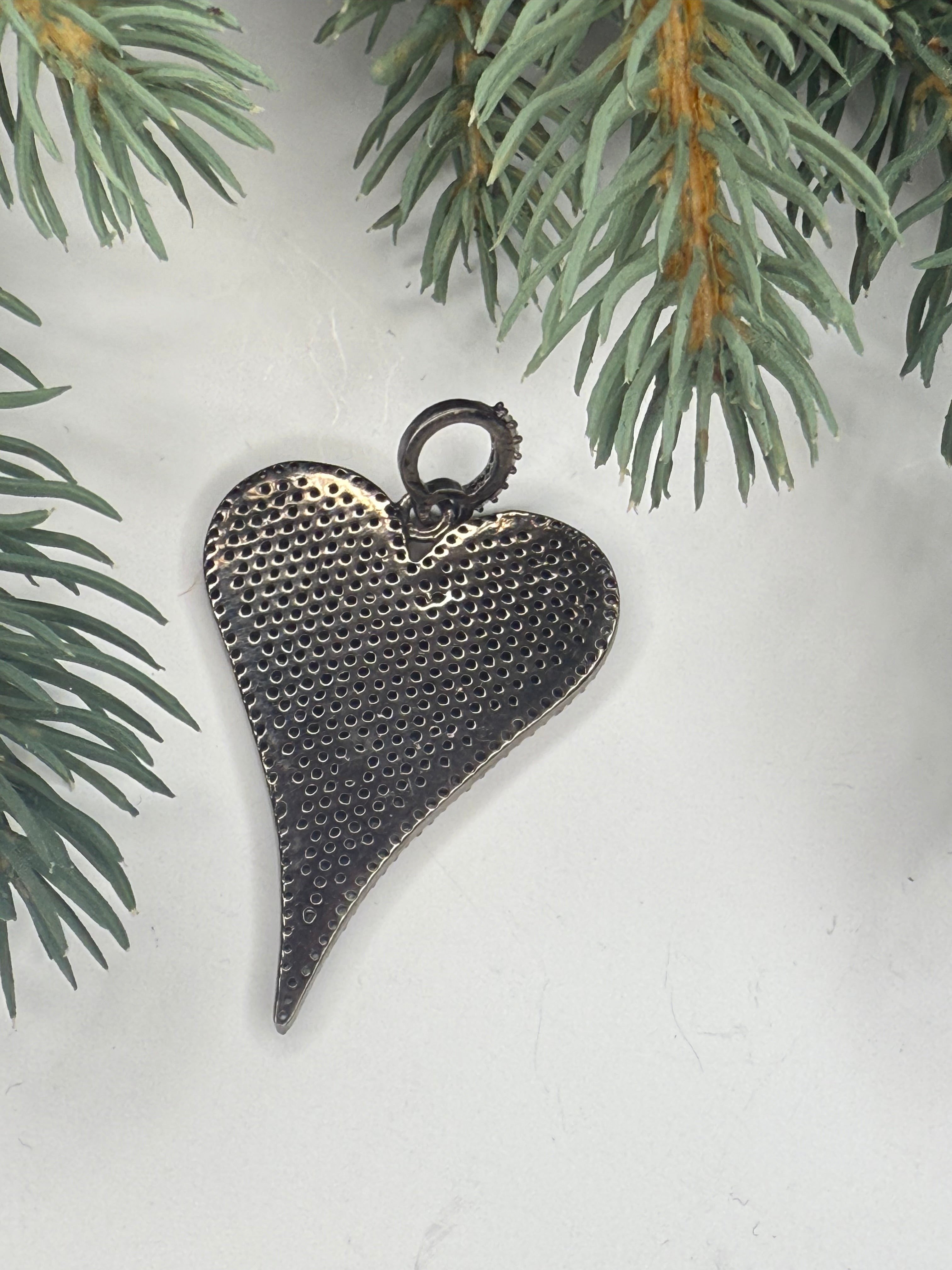 Back of heart-shaped pendant on a light background with greenery