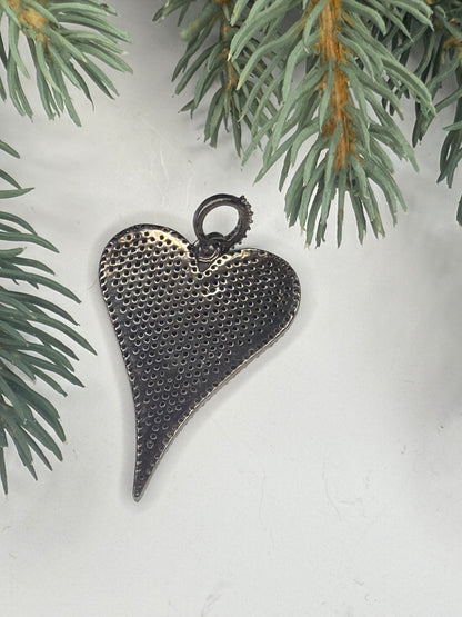 Back of heart-shaped pendant on a light background with greenery