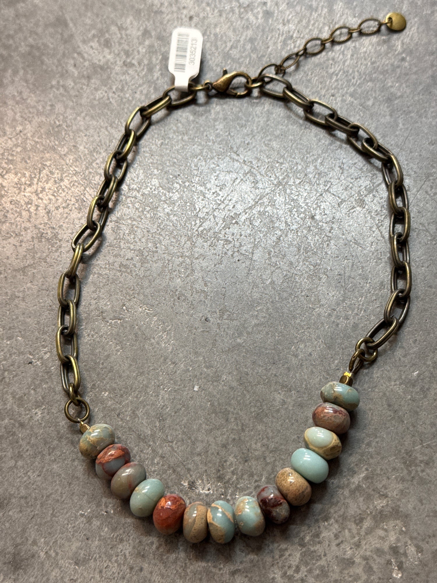 Necklace with beaded chain on a gray surface