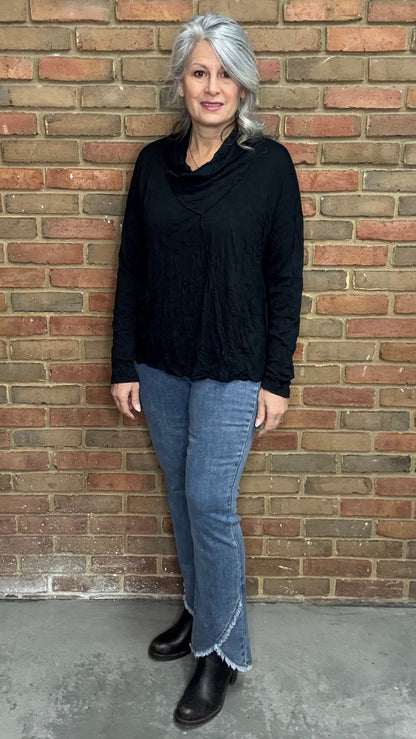 Person wearing a black top and the Front Tulip Hem Bootcut Pant standing against a brick wall.