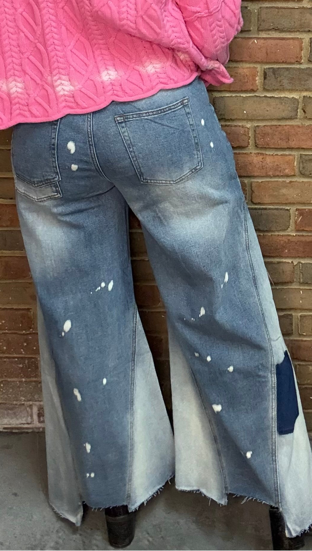 Woman wearing Bleached Wide Leg Jeans and Dusty Pink Ombre Sweater standing against a brick wall.