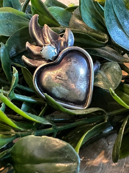 Flame Heart -T Ring on a green leafy background